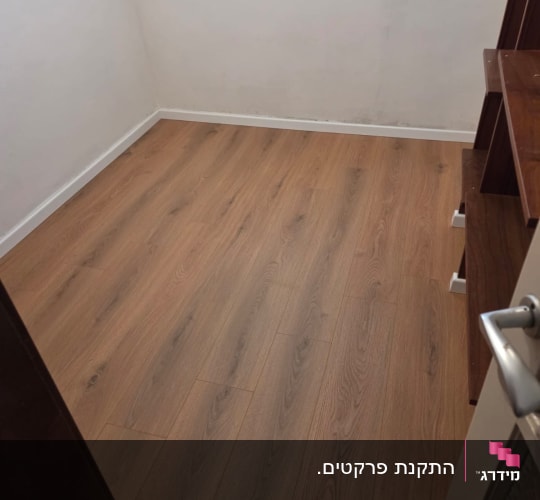 רצפת פרקט בחדר קטן עם קיר לבן